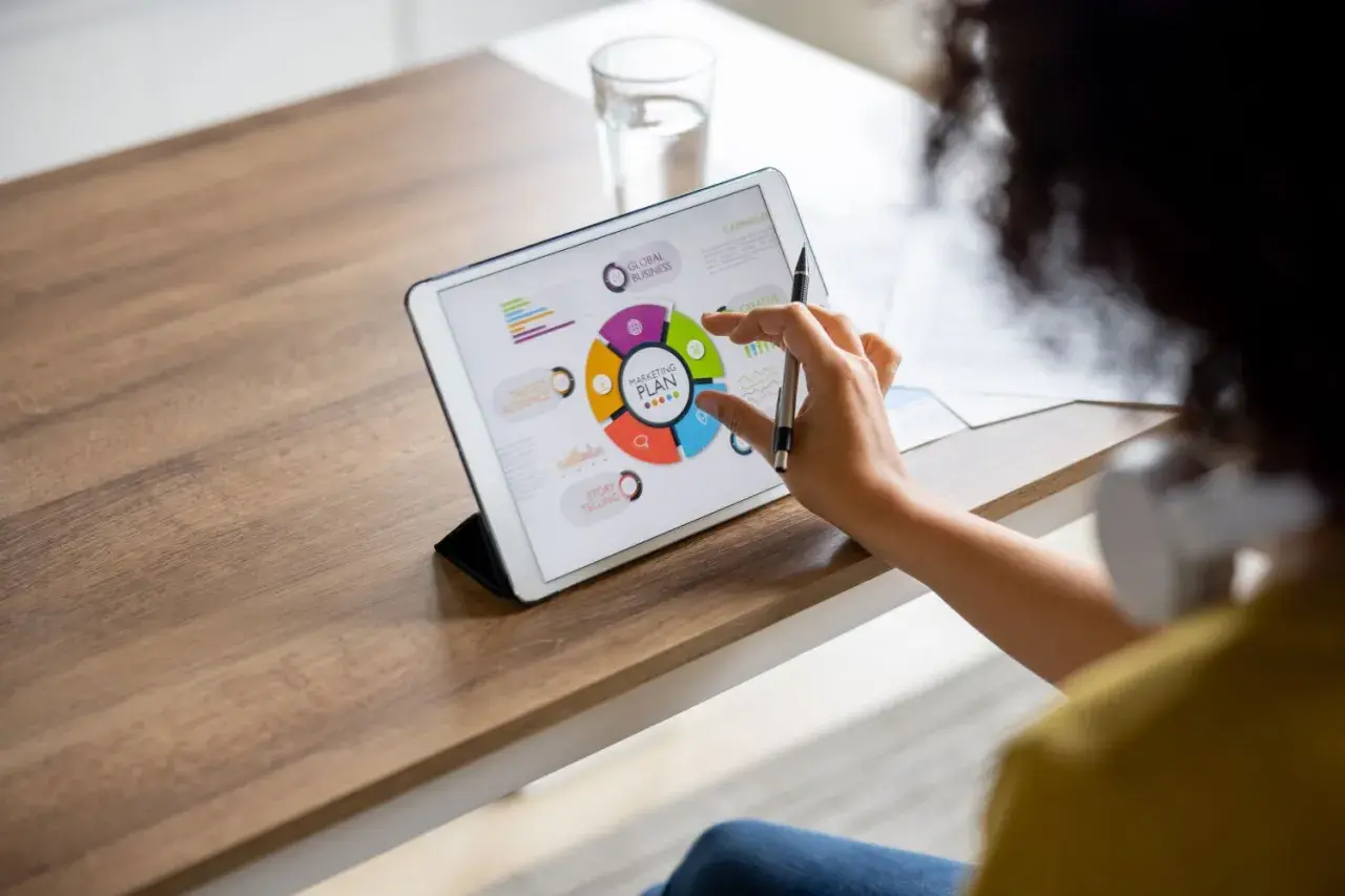 Kobieta pracuje nad planem marketingowym na tablecie, angażując się w **content co creation**.