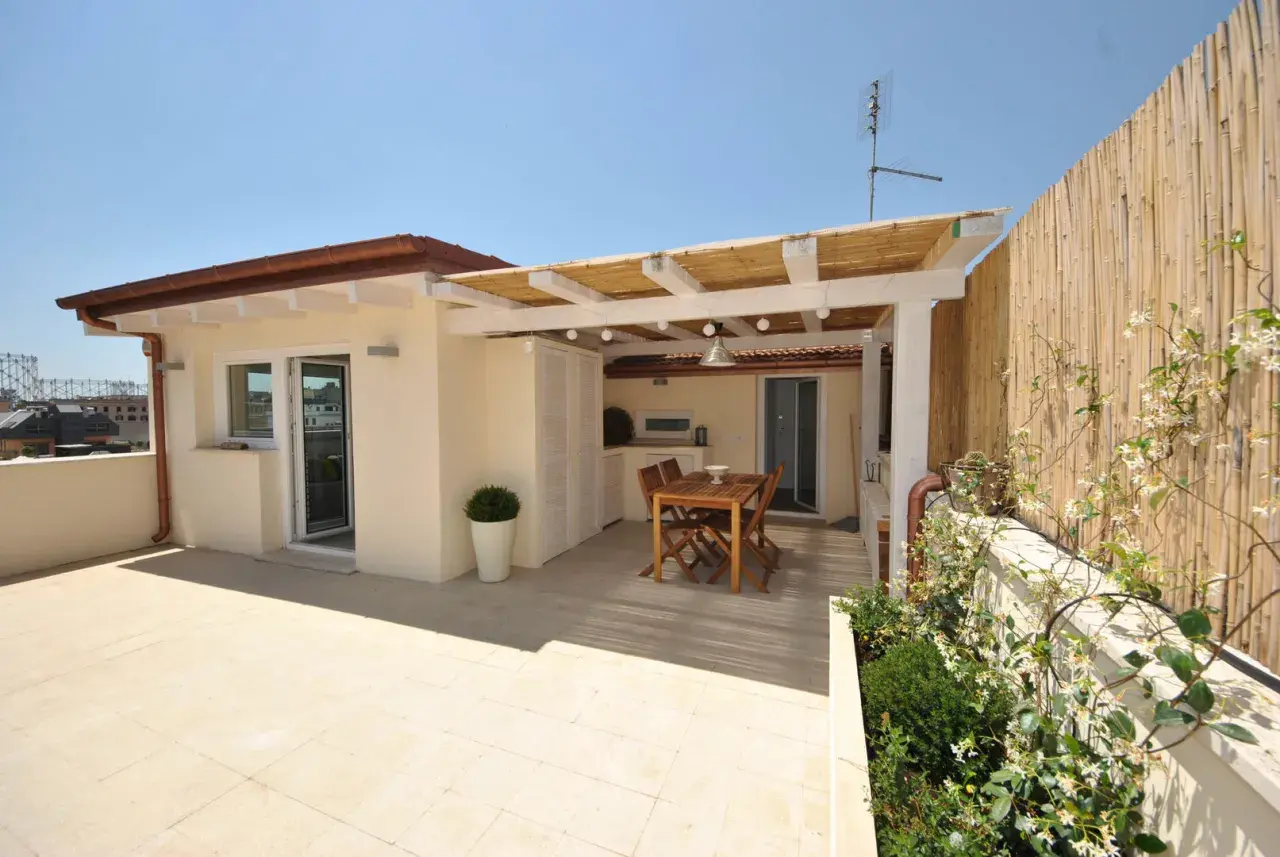 Un terrazzo sul tetto con tavolo in legno, pergola di bambù e vista sulla città. Ideale per cene all'aperto.