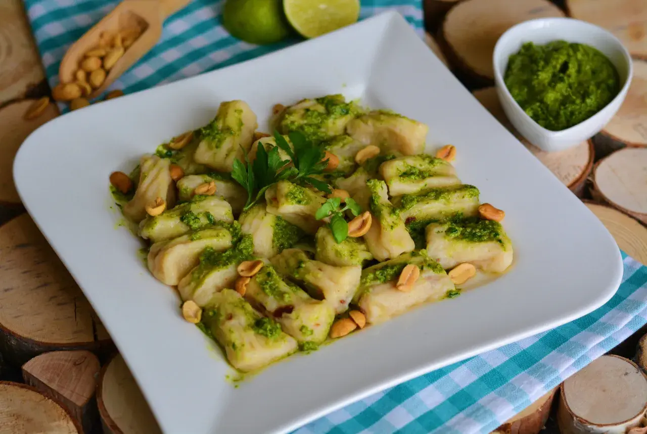 Pyszne gnocchi z pesto, posypane orzeszkami ziemnymi i udekorowane natką pietruszki. Idealne danie dla miłośników włoskich smaków.