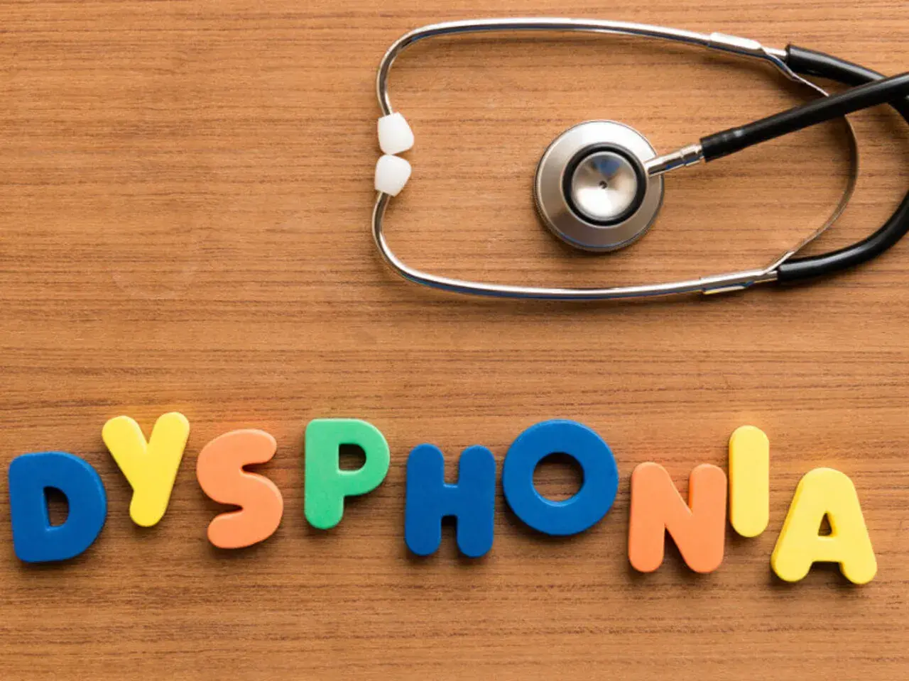 Kolorowe litery układają się w napis "DYSPHONIA", a obok leży stetoskop. To symbol problemów ze struny głosowe inaczej.