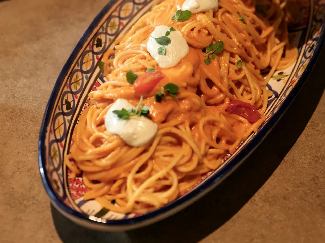 Un invitante piatto di pasta con pomodorini, condita con una cremosa salsa e guarnita con ricotta fresca e basilico.