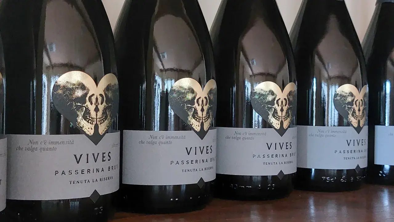 Bottiglie di Vives Passerina Brut, un vino fermo o frizzante, con etichetta a forma di cuore con teschio dorato.
