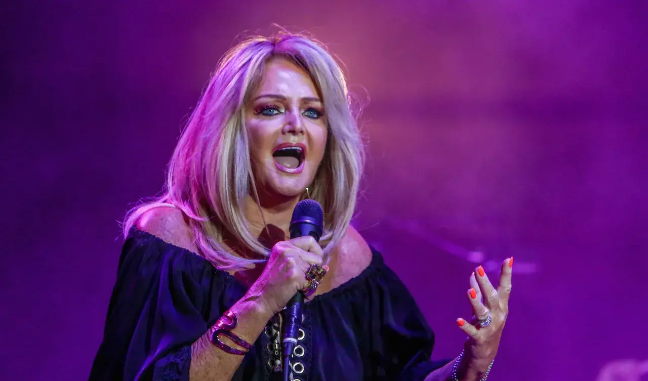 Eine Frau mit blonden Haaren singt leidenschaftlich ins Mikrofon, als würde sie ihre liebsten Karaoke-Songs performen.
