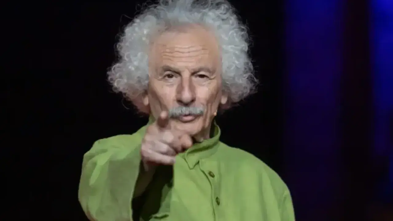 El brujo del Teatro de las Esquinas, con su melena blanca y camisa verde, señala al público.
