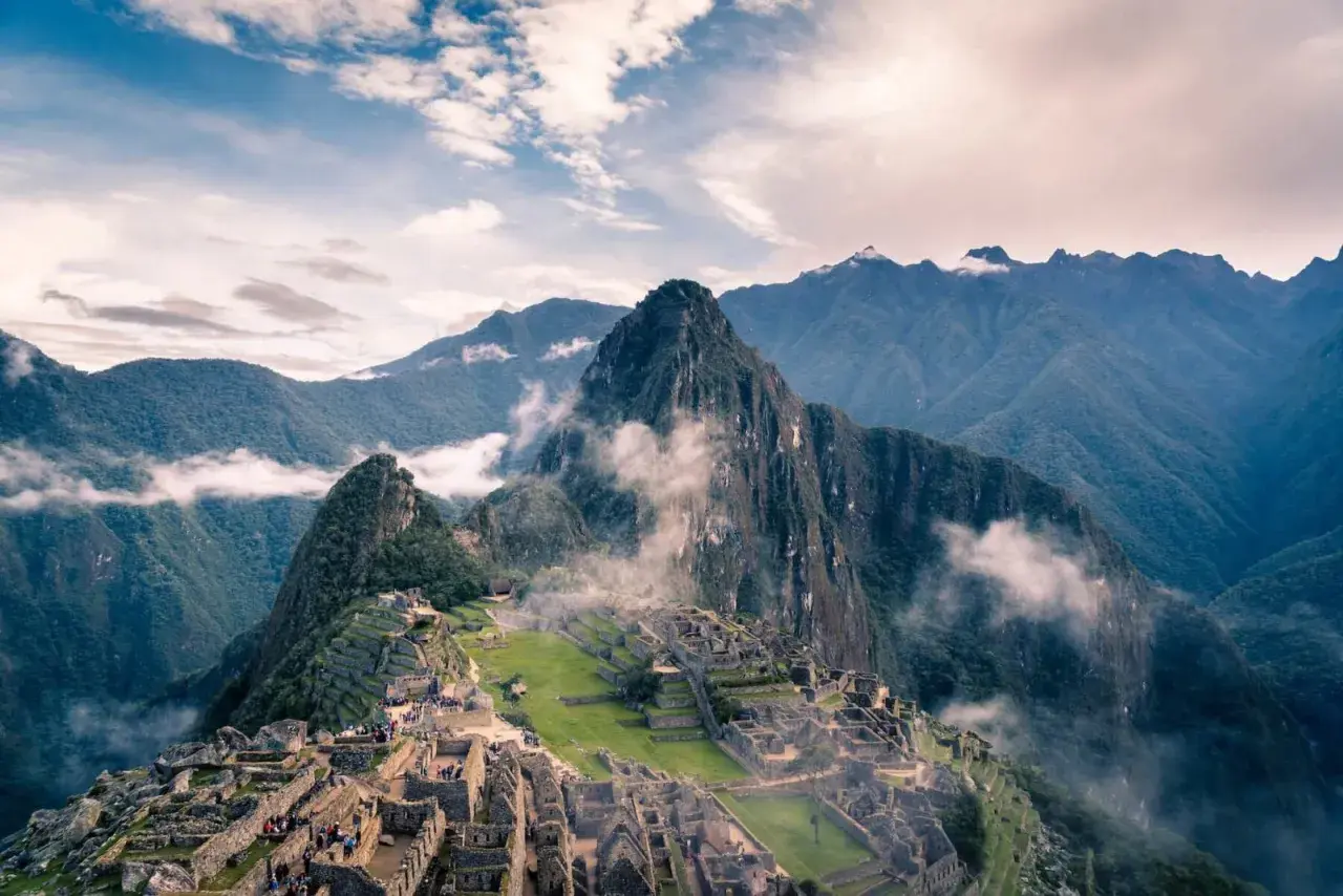 Die Ruinen von Machu Picchu, eingebettet in nebelverhangene Andengipfel. Ein atemberaubender Blick auf die Inka-Stadt, die sich an die Berghänge schmiegt.