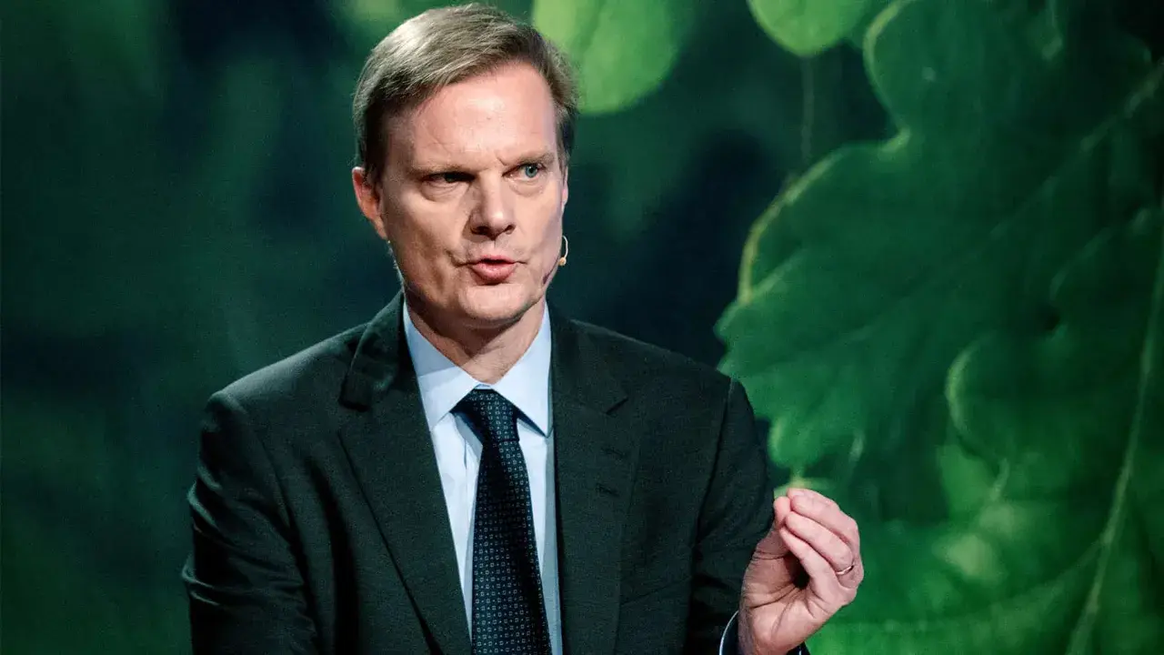 Jens Henriksson, VD för Swedbank, talar med en gest. Bakgrunden är grön med stora blad.