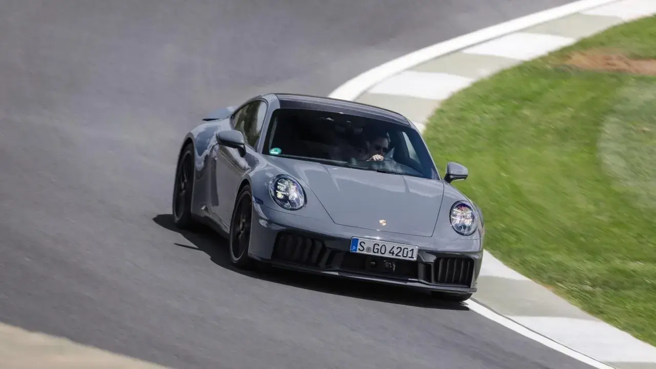Un'auto sportiva ibrida grigia sfreccia su una pista, con il guidatore concentrato.
