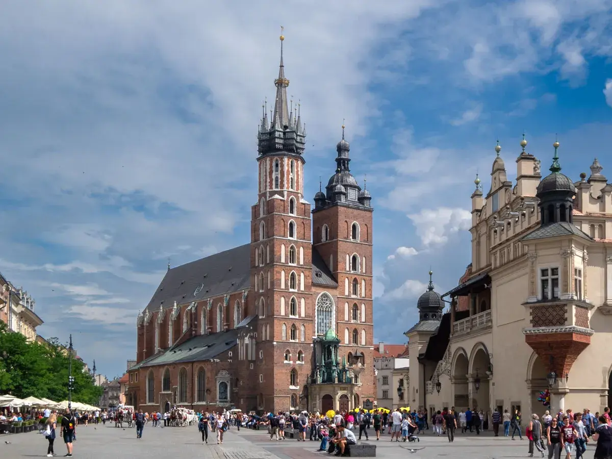 Majestatyczna Bazylika Mariacka w Krakowie góruje nad Rynkiem Głównym, gdzie tętni życie.