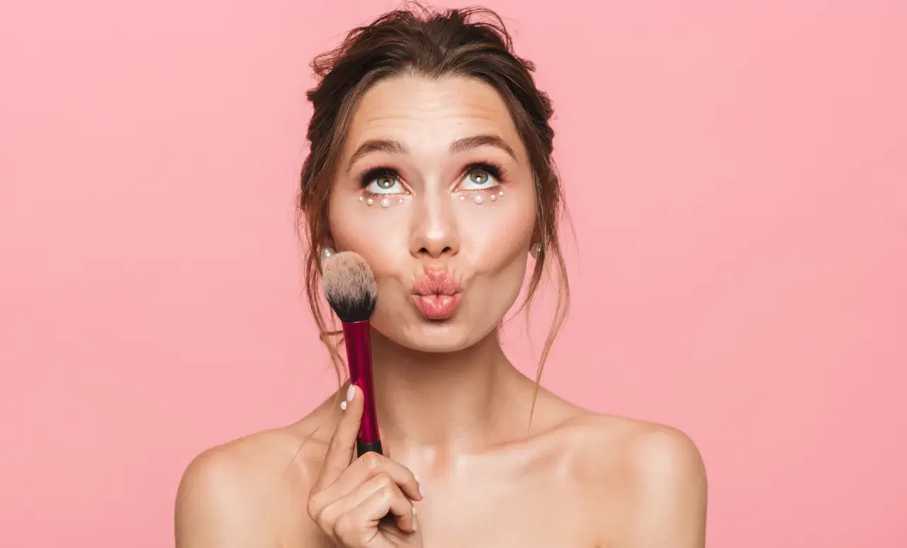 Jeune fille avec un maquillage simple et des perles sous les yeux, tenant un pinceau. Idéal pour un maquillage simple pour jeune fille.