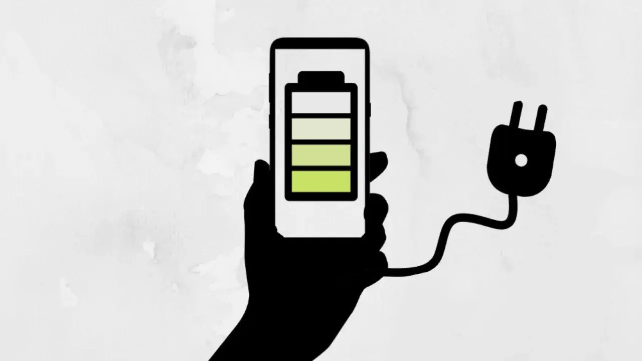 Mano sosteniendo un teléfono con batería a 3/4, conectado a un enchufe. ¡Un truco para el ahorro de batería!