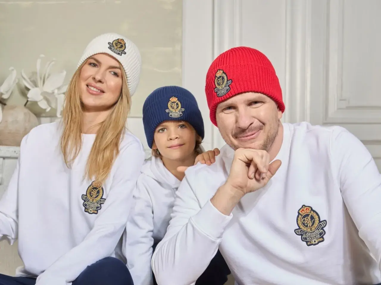 Filip Chajzer z rodziną w czapkach i bluzach z herbem. Uśmiechnięty tata, mama i ich dzieci.