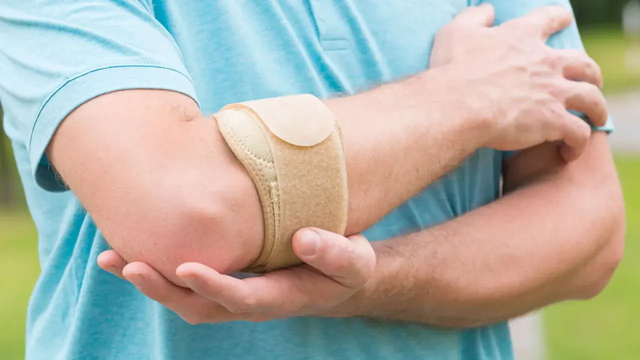 Mann mit Bandage am Ellenbogen, um den **Tennisellenbogen** zu lindern.