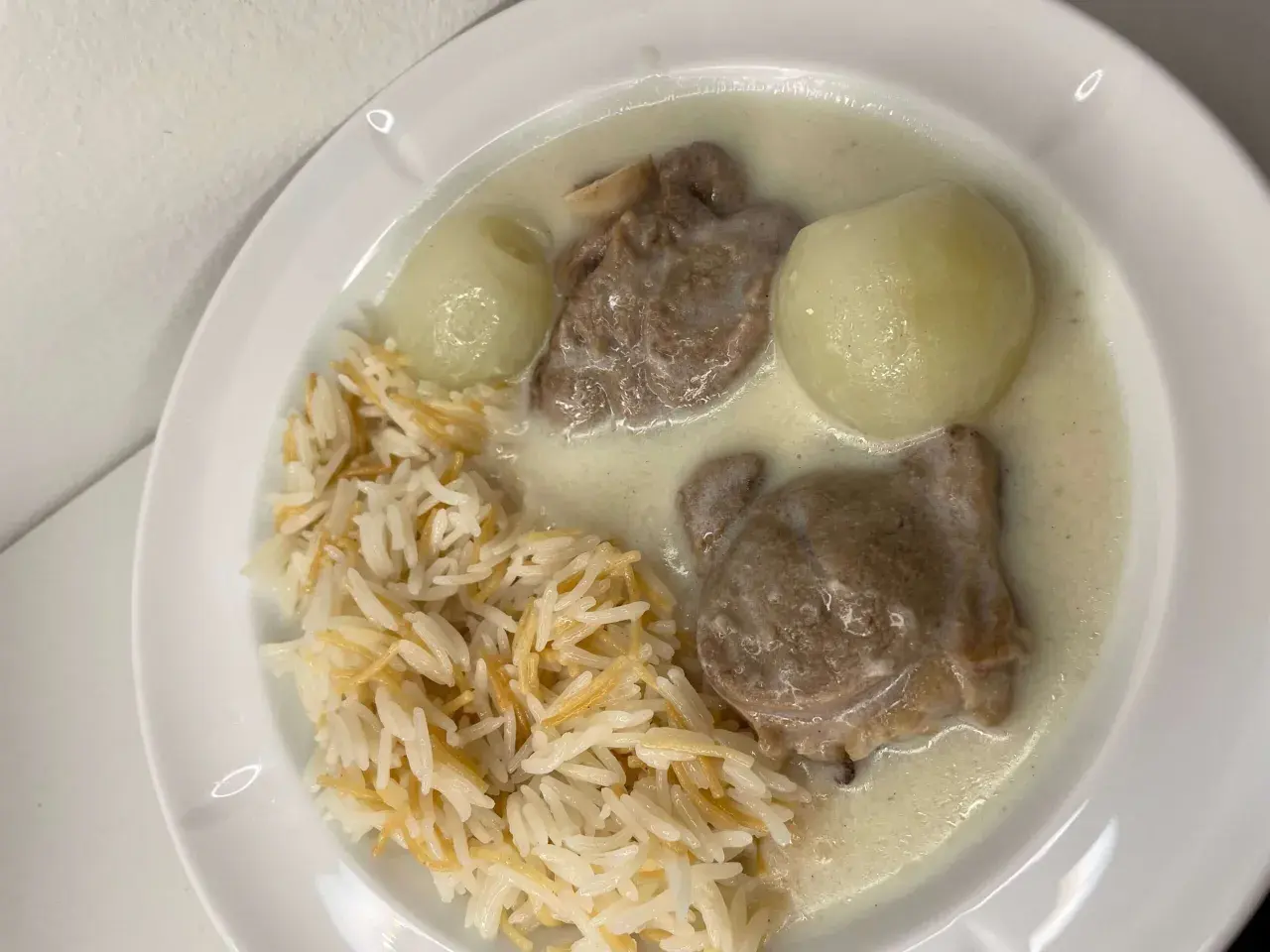 En tallrik med ris, köttbitar i en krämig sås och två hela kokta lökar. En riktig laban emo-måltid!