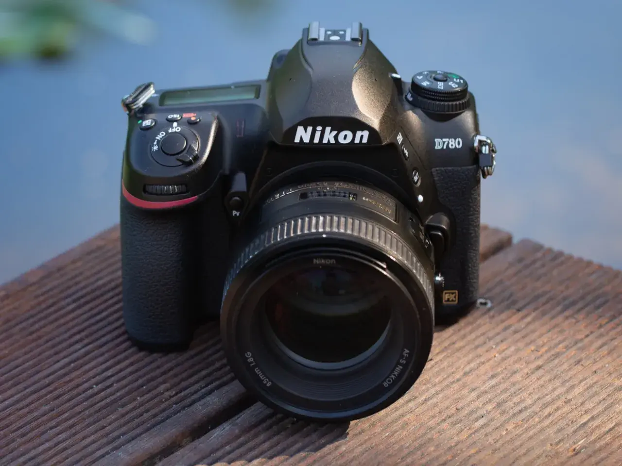Nikon D780 z obiektywem 85mm f/1.8G na drewnianym pomoście. Aparat gotowy do testów.