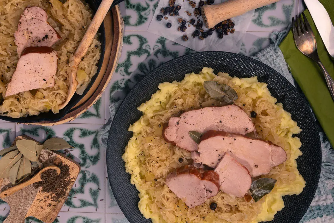 Kassler in Sauerkraut mitkochen wie lange? Zartes Kassler auf Sauerkraut mit Kartoffelpüree, garniert mit Lorbeerblättern und Kümmel.