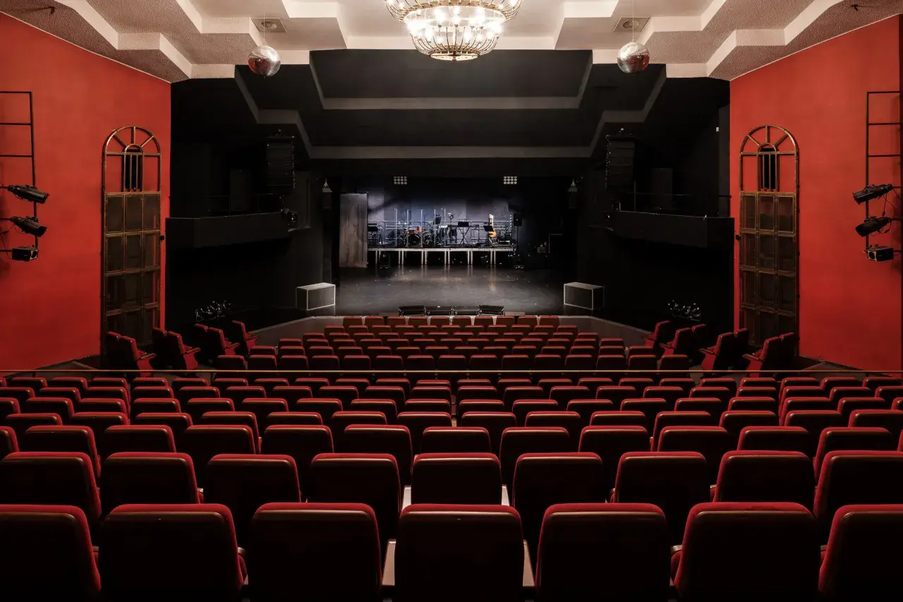 Widownia teatru na Targówku, z rzędami czerwonych foteli i sceną gotową na występ.