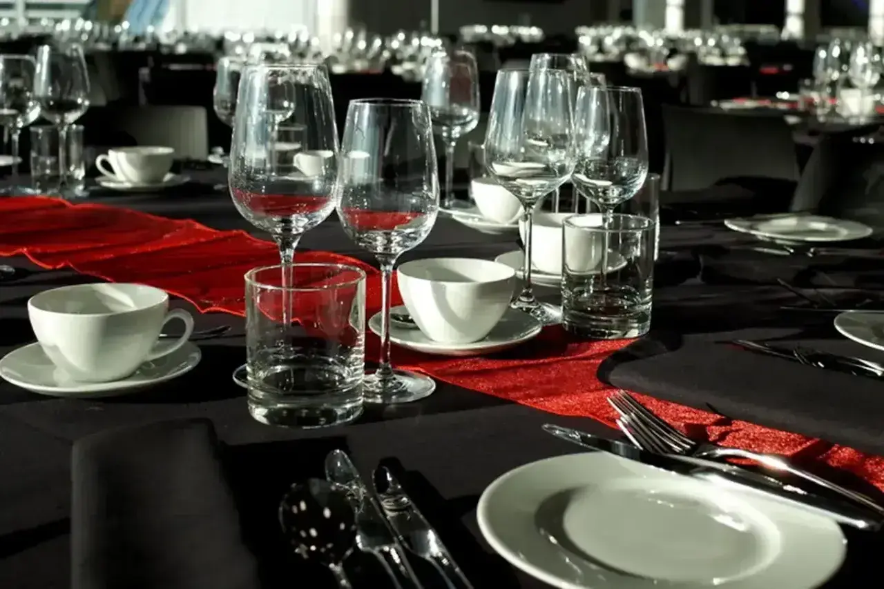 Elegancko nakryty stół na stypę, z kieliszkami do wina i szklankami, sugeruje, że alkohol może być serwowany.