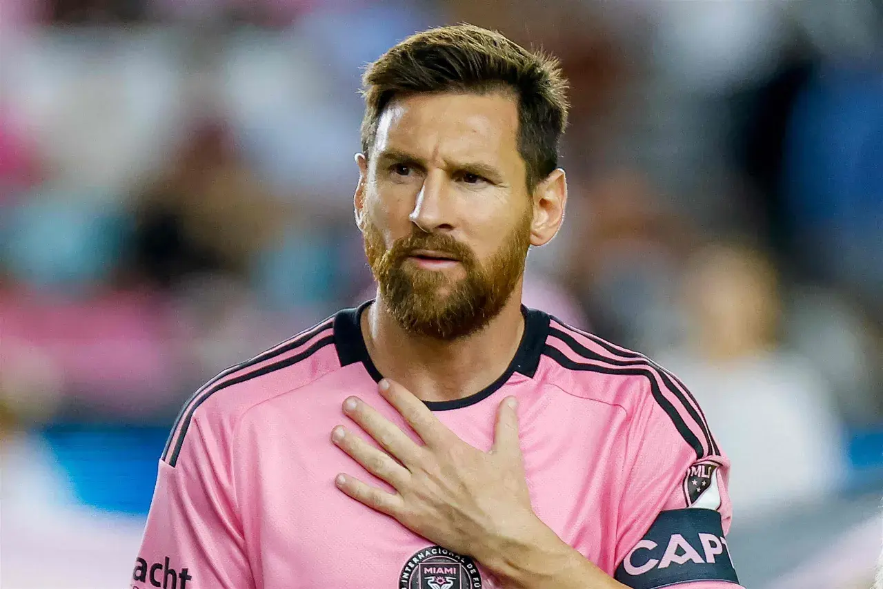 Piłkarz w różowej koszulce z opaską kapitana, z ręką na sercu. Plotki o tym, że messi nie żyje, są fałszywe.