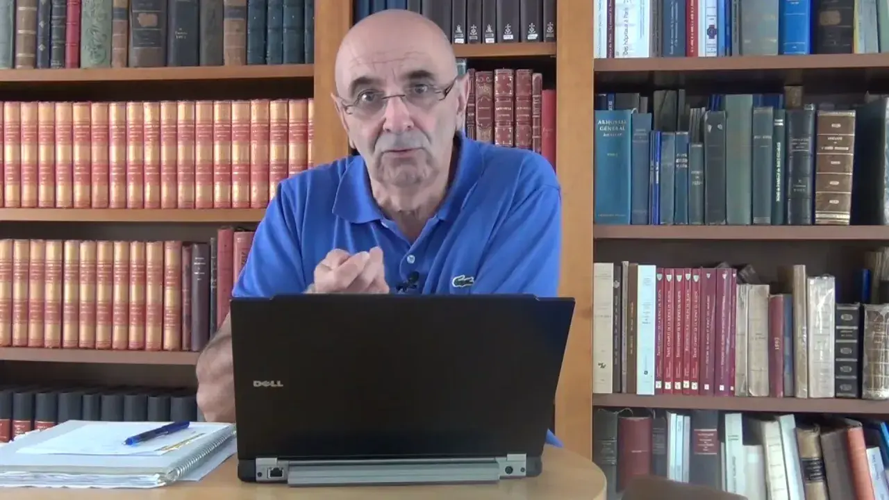 Un homme parle devant un ordinateur portable, entouré de livres. Il semble discuter de l'ad 07 état civil.