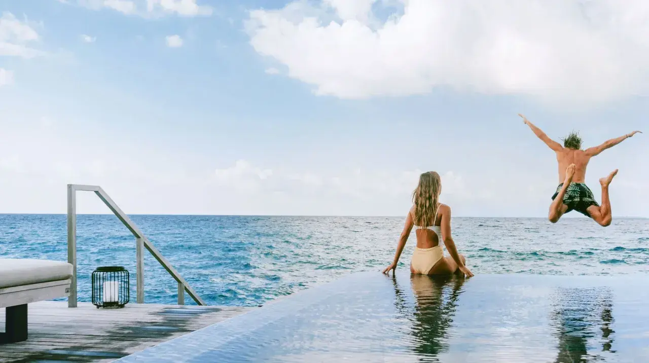 Ein Mann springt ins Meer, während eine Frau zusieht. Perfekte tschechien urlaub tipps für sonnige Tage am Wasser.