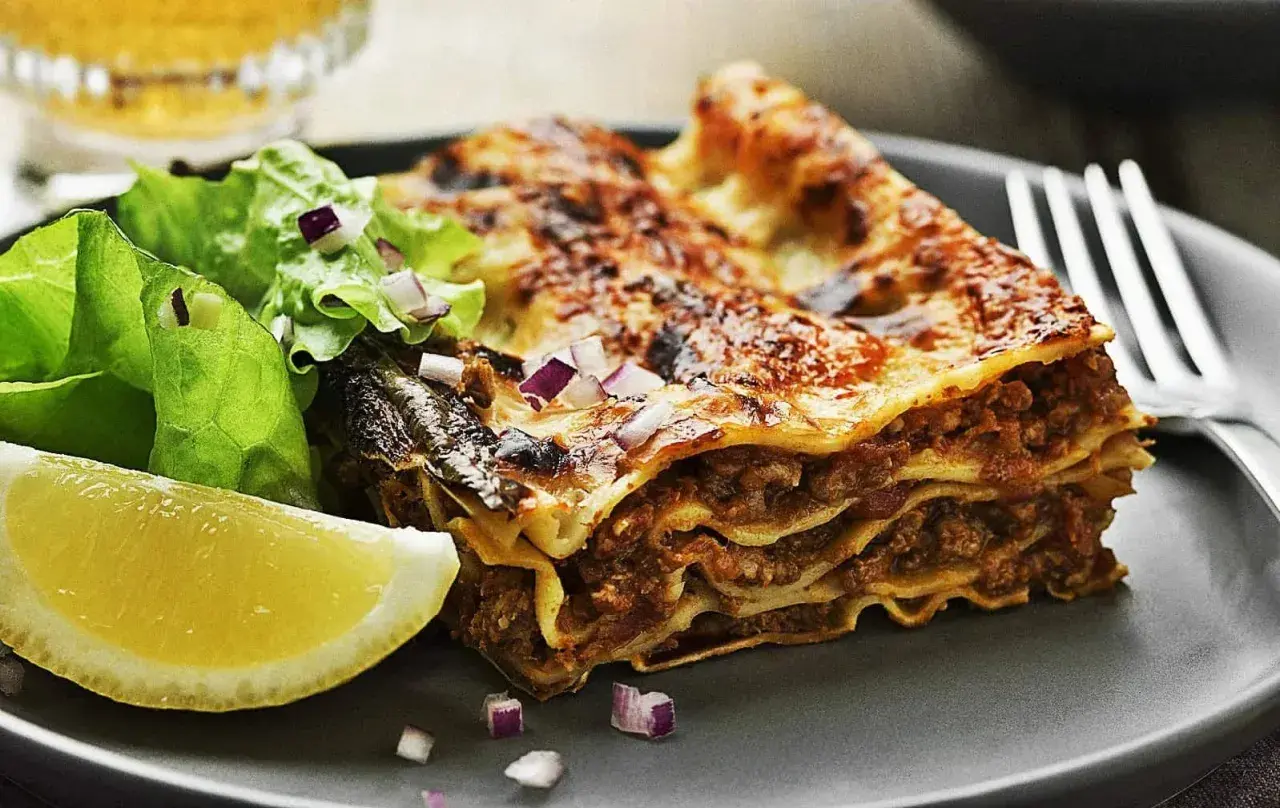 En saftig bit lasagne med köttfärs och ost, serverad med en fräsch sallad och citronklyfta. Perfekt för lasagnens dag!
