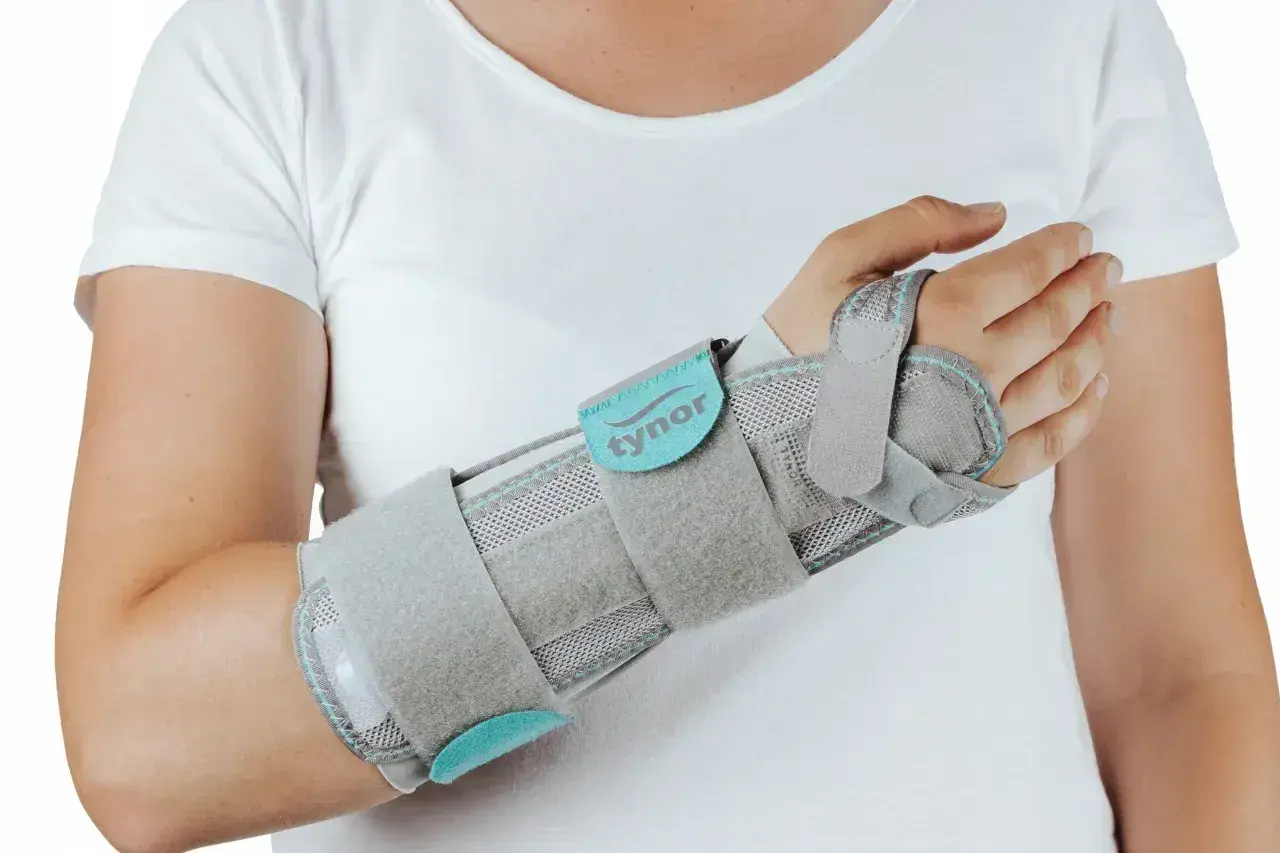 Szara orteza na nadgarstek, która zapewnia stabilizację, lepsza niż gips.