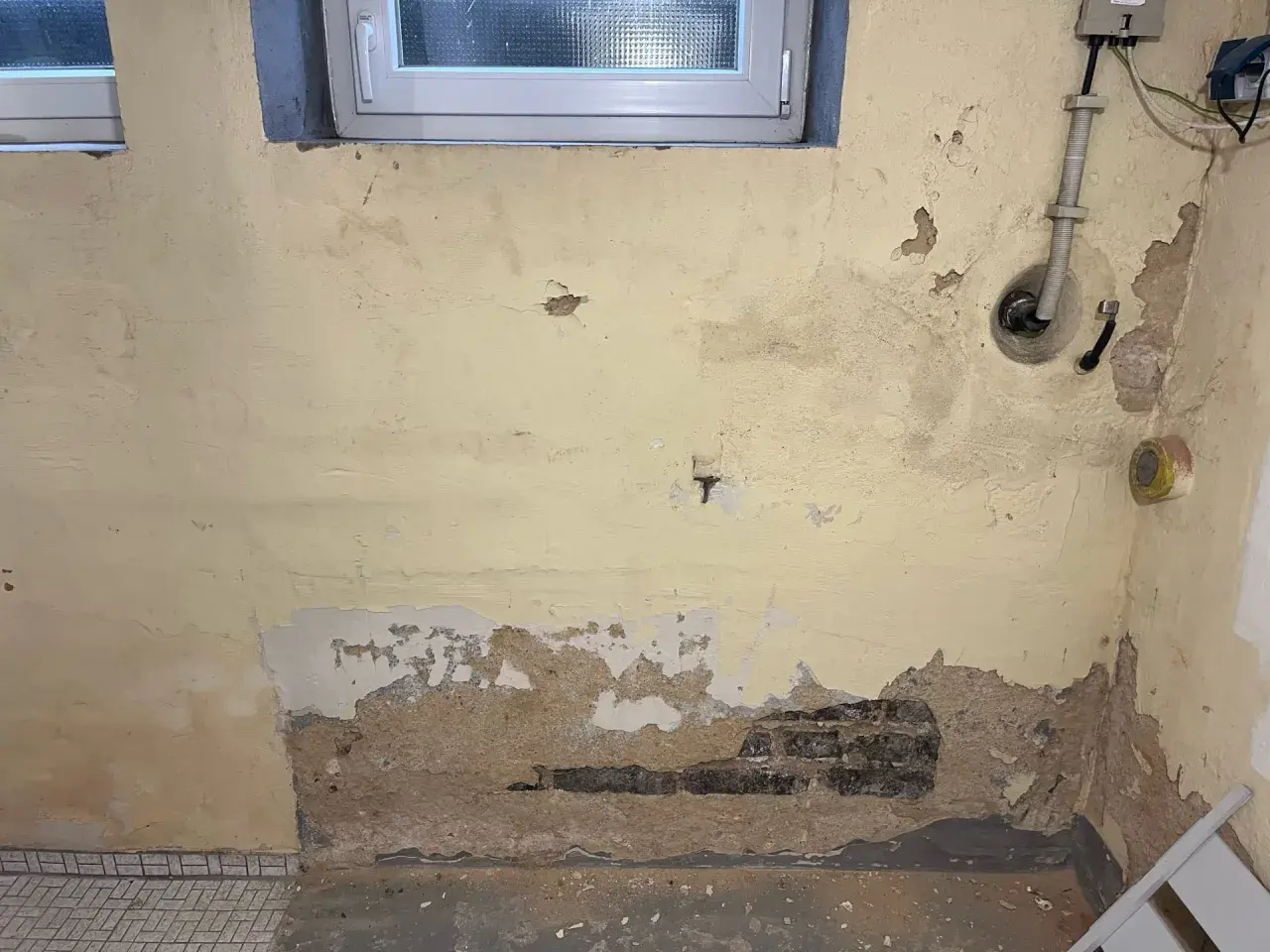 Feuchte Wände im Altbau: Putz bröckelt, Ziegel sind sichtbar. Zeit für eine professionelle Keller trockenlegen Maßnahme.
