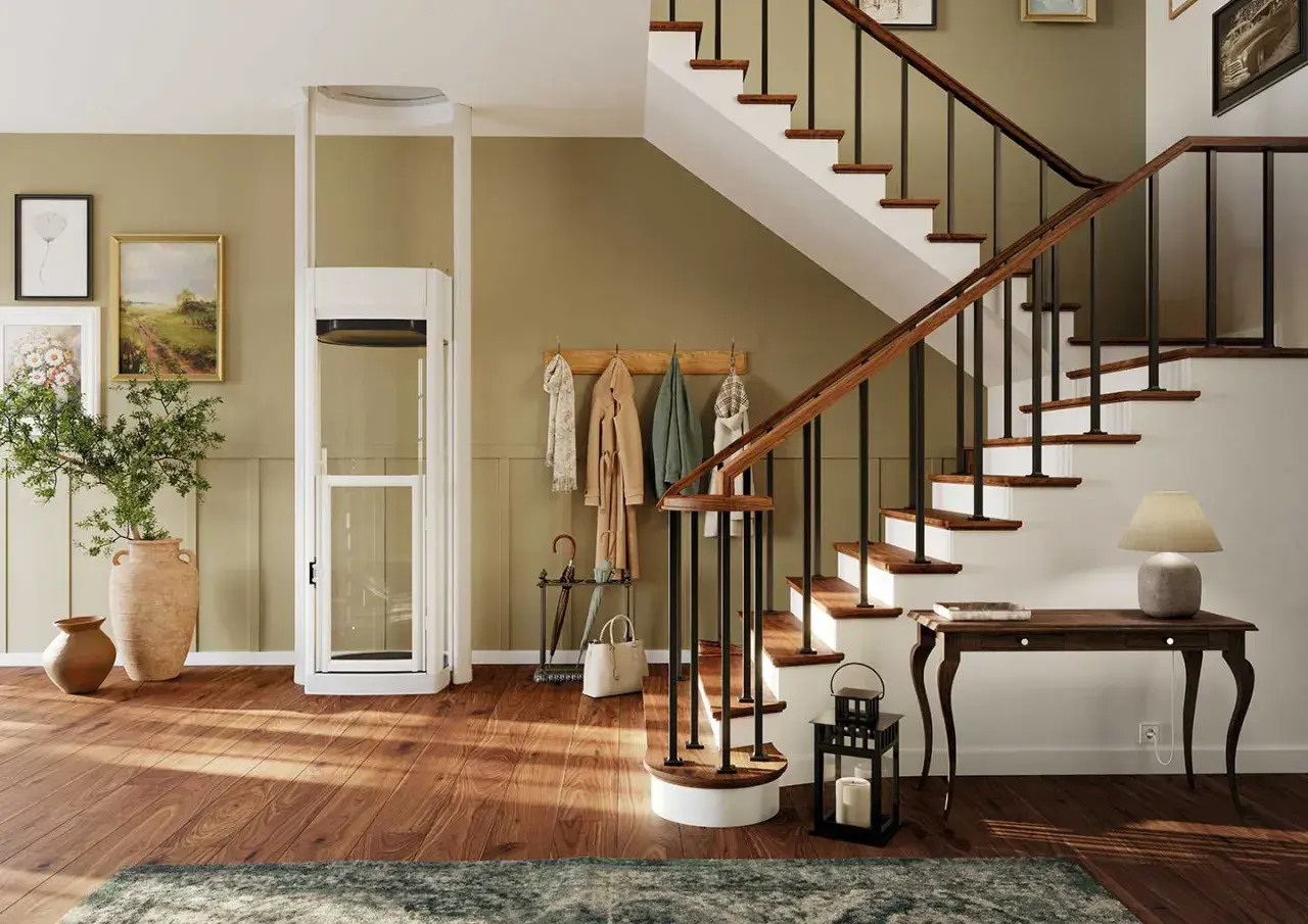 Ein moderner Treppenlift mit Glaskabine steht neben einer Holztreppe. Bilder und Garderobe schmücken die Wand.