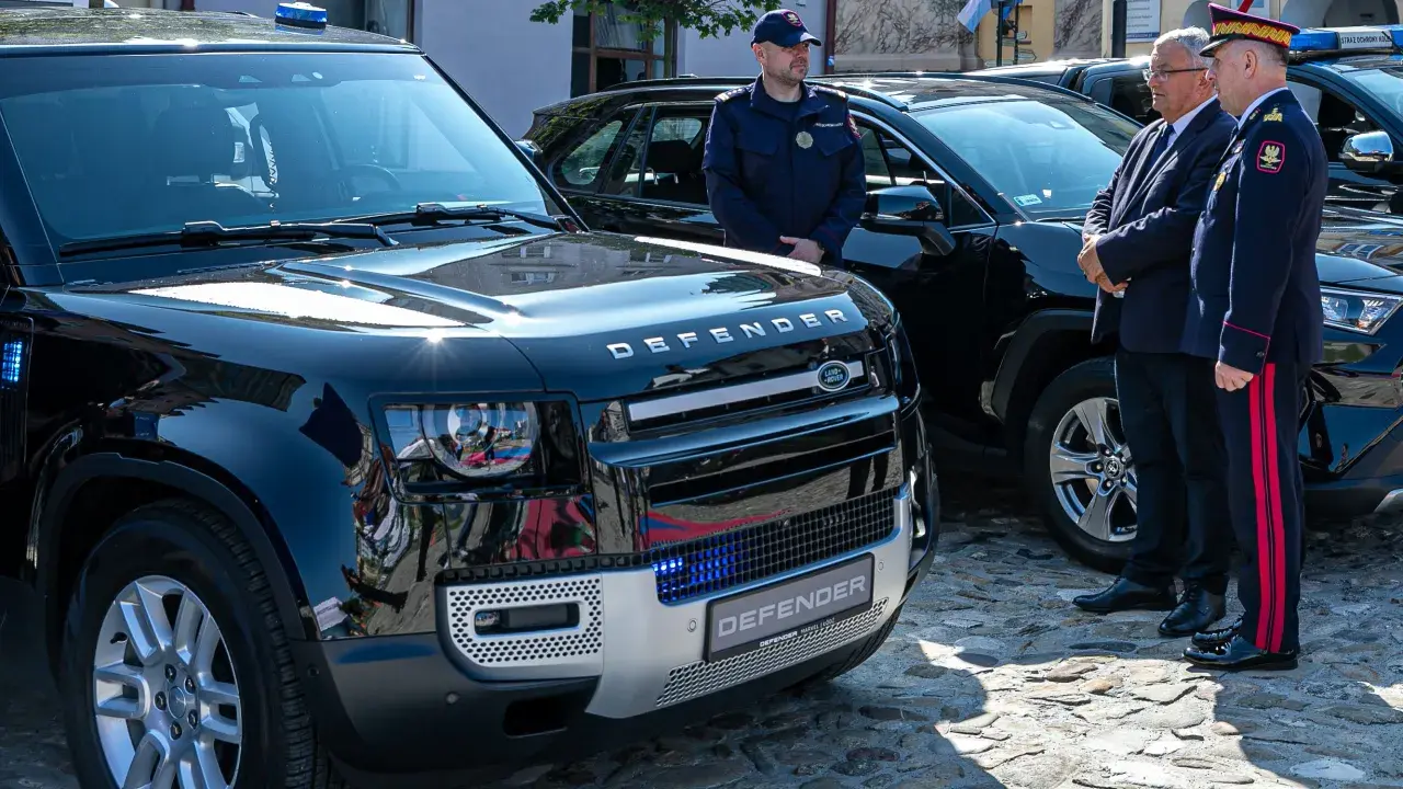 Nowy Land Rover Defender, mały pojazd szynowy, lśni w słońcu. Obok stoją funkcjonariusze w mundurach.
