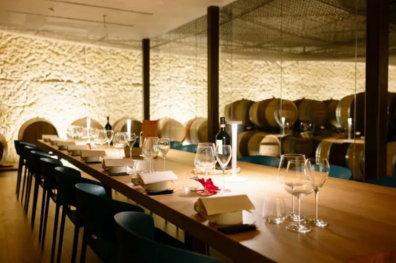 Tavola apparecchiata in una cantina dei vini, con botti sullo sfondo.