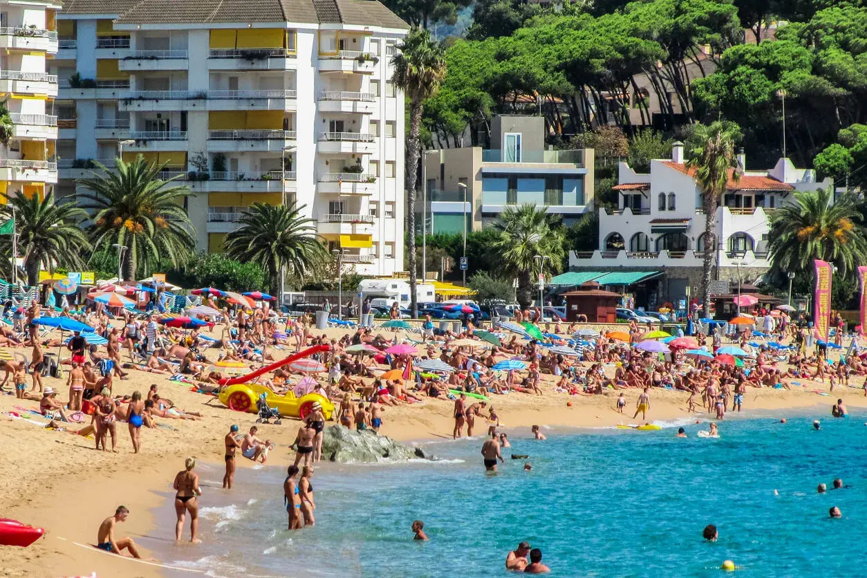 Lloret de Mar pogoda kwiecień: plaża pełna ludzi, słońce, palmy i turkusowe morze. Idealny dzień na wypoczynek.