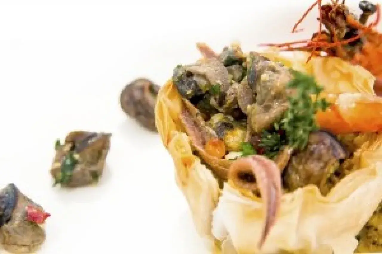 Wykwintne danie ze ślimaków w cieście filo, idealne na ślimak catering Kraków. Krewetka i zioła dopełniają kompozycję.