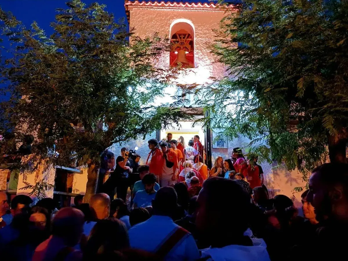 Multitud reunida frente a una iglesia iluminada, disfrutando de las fiestas de Calatayud.