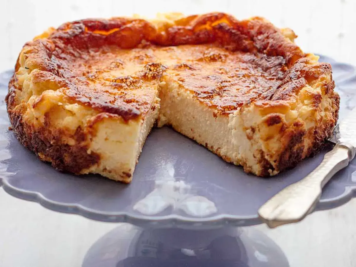 Tarta de queso de la Viña, dorada y cremosa, servida en un plato morado.