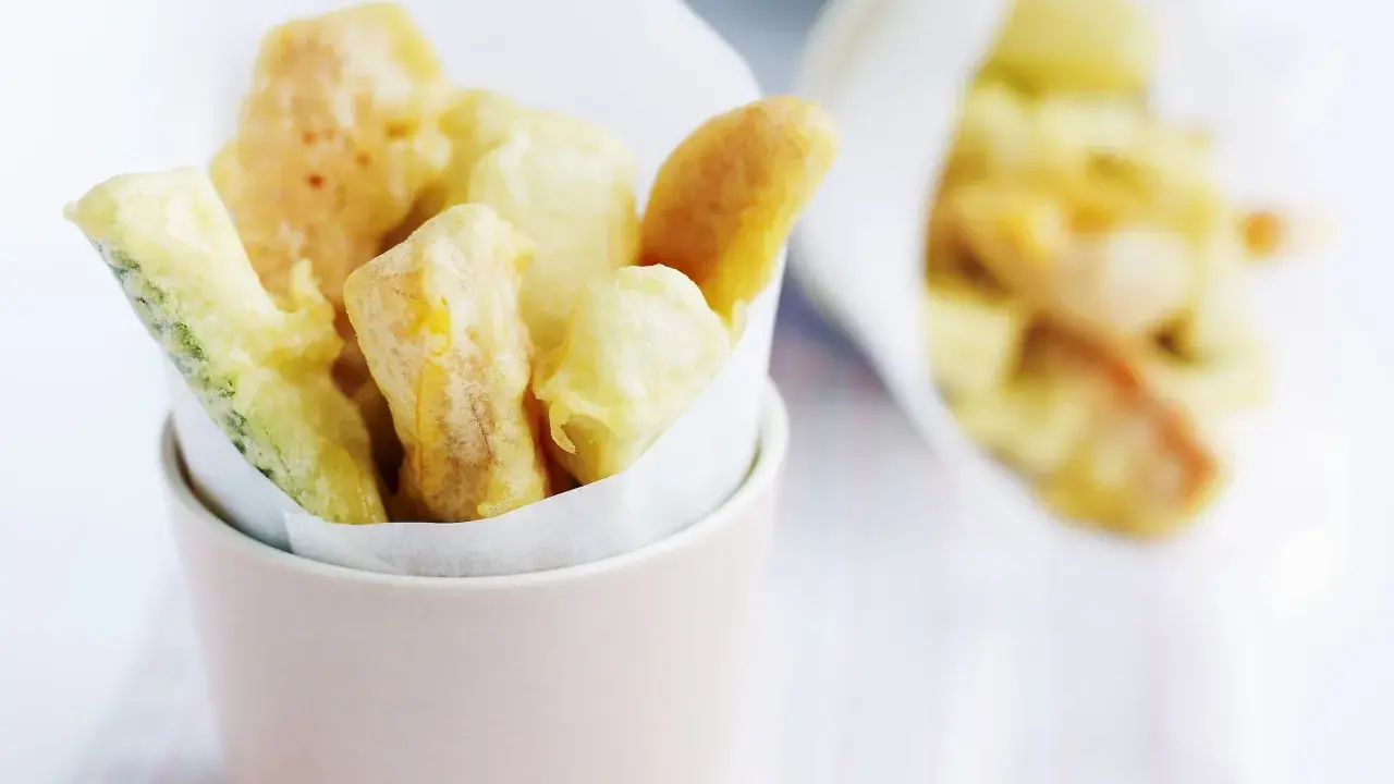 Verdure croccanti immerse in una leggera pastella per verdure fritte, servite in un contenitore rosa.