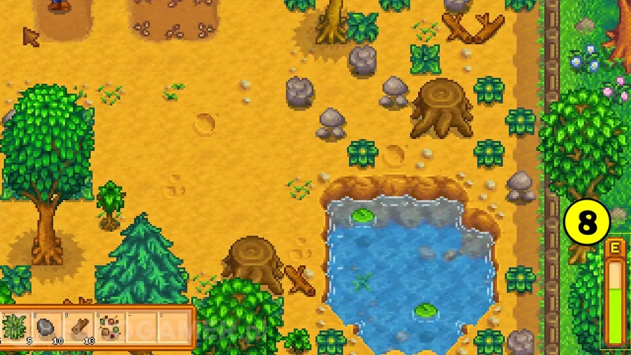 Stardew Valley poradnik: farma z drzewami, kamieniami, stawem i ikoną "8".