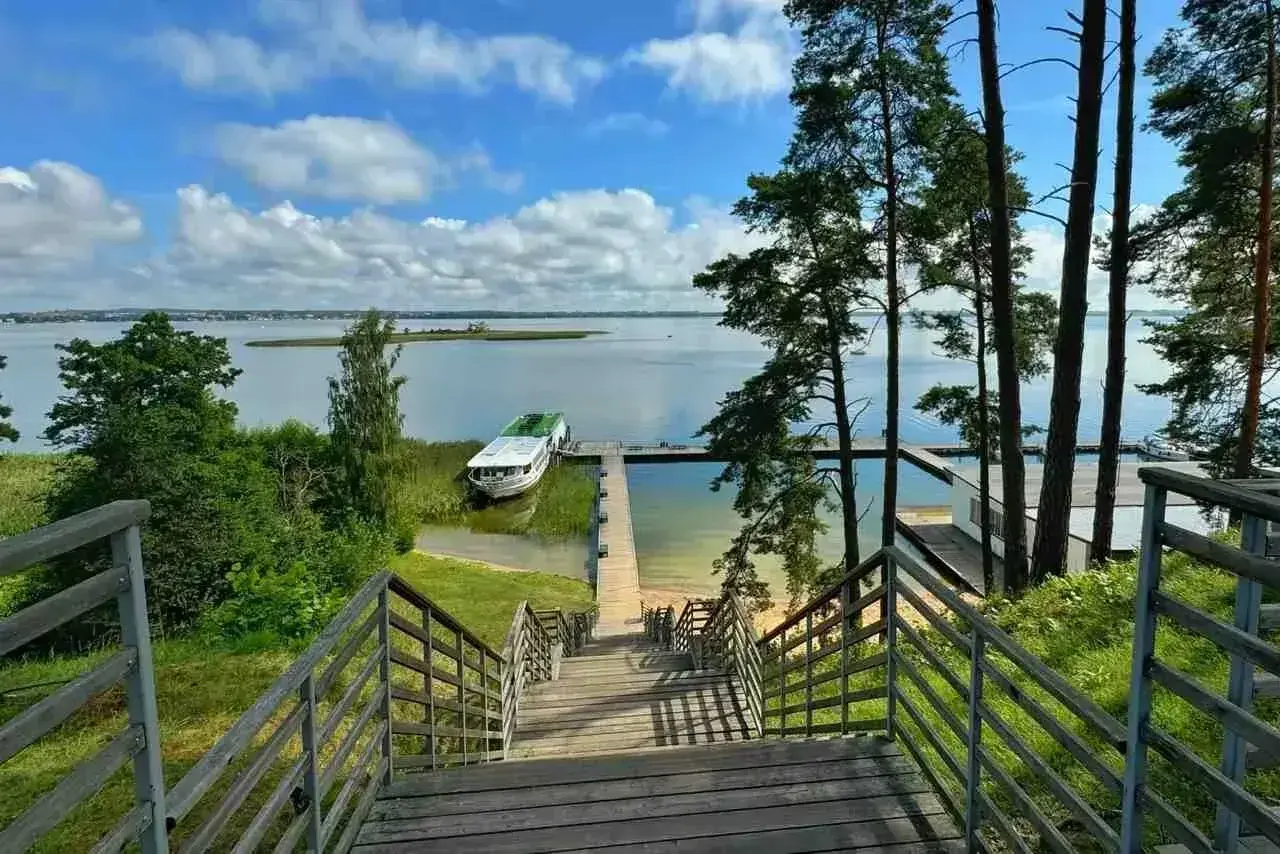 Idealne miejsce na mazury na weekend. Drewniane schody prowadzą do jeziora, gdzie cumuje statek.