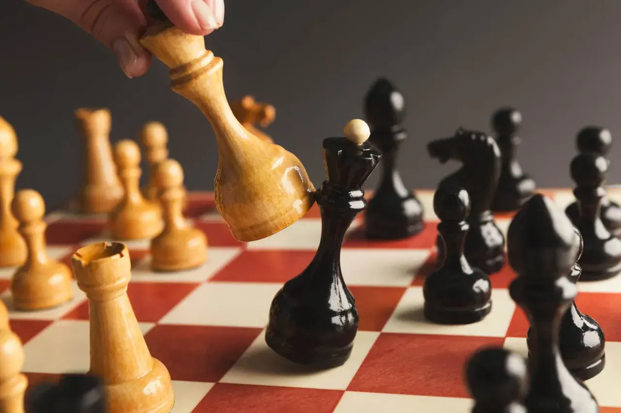 Ręka przesuwa jasnego króla, by zbić czarnego króla. Strategia jak sprzedać akcje.