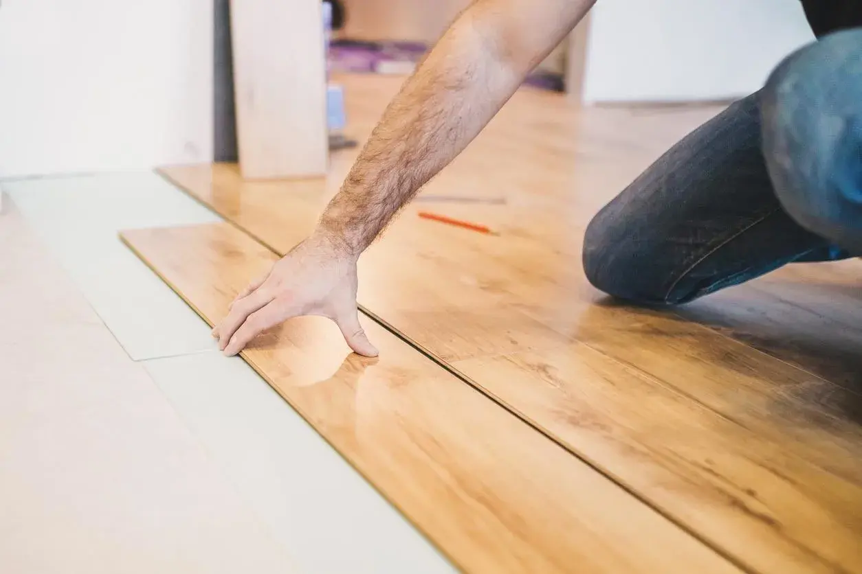 Installazione di parquet laminato: un uomo posa le tavole, mostrando come tagliare spc.
