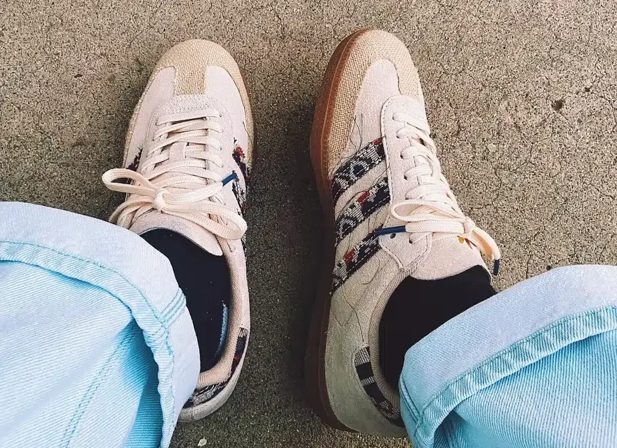 Un homme porte des sneakers Adidas beige avec des détails ethniques, un outfit décontracté parfait pour la belle saison.
