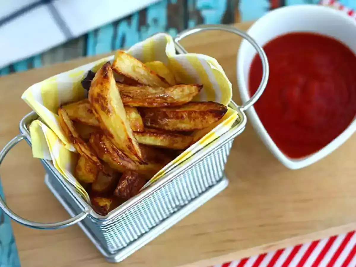 Un panier rempli de délicieuses frites au four dorées, à côté d'un bol de ketchup rouge vif.