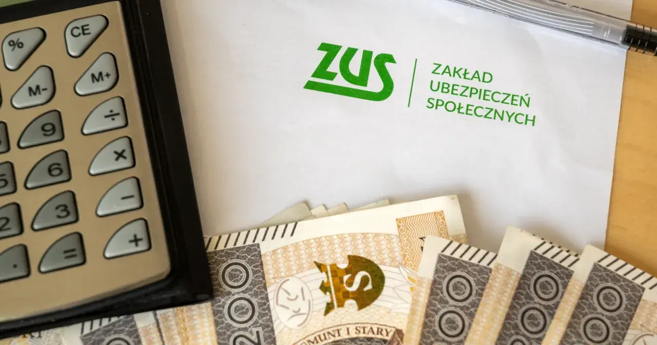Kalkulator, banknoty i dokument ZUS. Obrazek nawiązuje do tematu zasiłku przedemerytalnego i finansów.