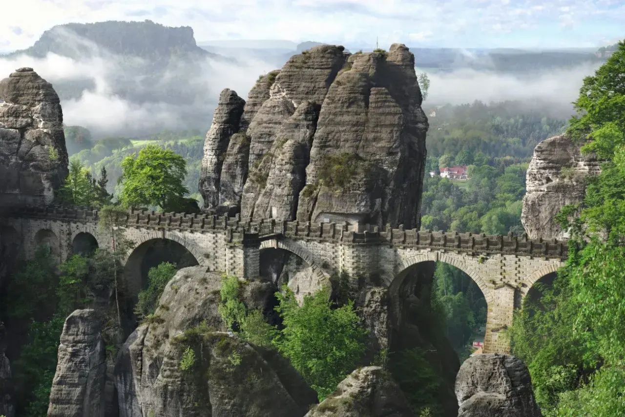 Kamienny most Bastei, jedna z najpiękniejszych atrakcji turystycznych Saksonii, wznosi się nad skalistym wąwozem, otoczony mglistymi górami.
