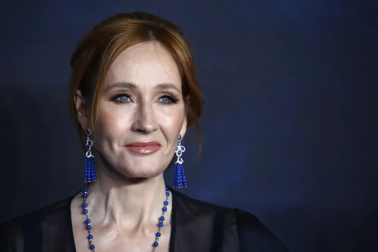 J.K. Rowling z rudymi włosami, niebieskimi oczami i niebieskimi kolczykami.