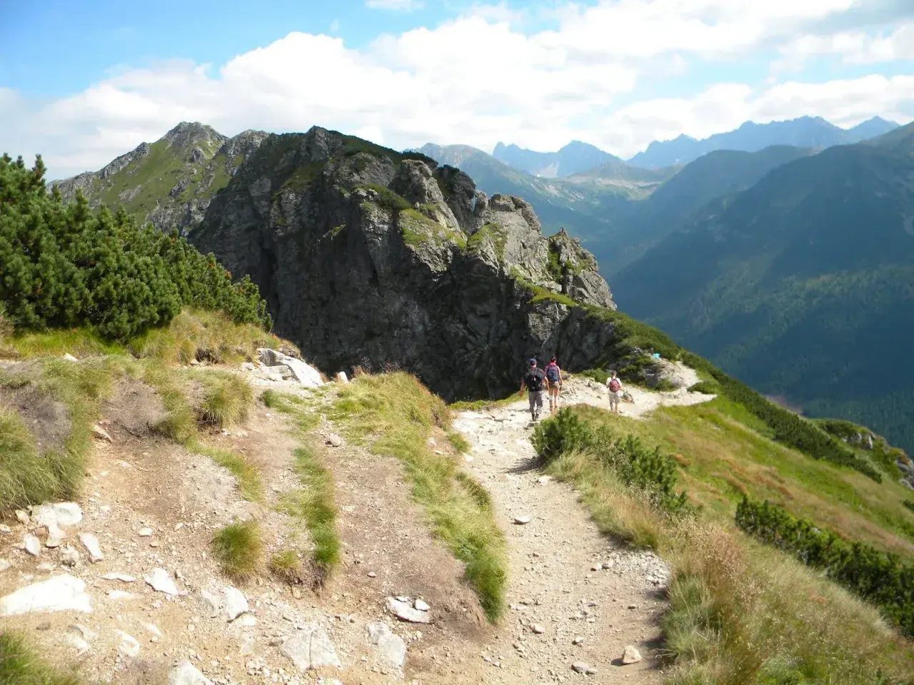 Grupa turystów wędruje malowniczym szlakiem w Tatrach. Widok na góry i doliny, idealne tatry szlaki dla średnio zaawansowanych.