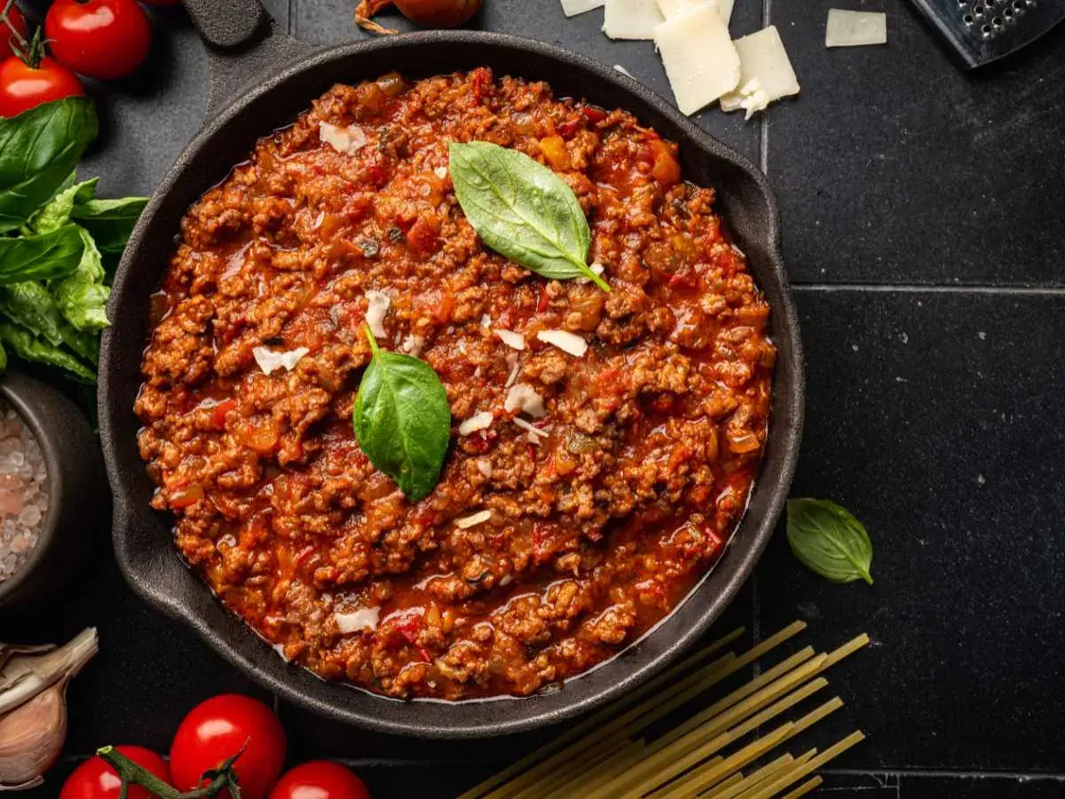 Un delicioso plato de spaghetti bolognese original, con carne picada, tomate y albahaca fresca.