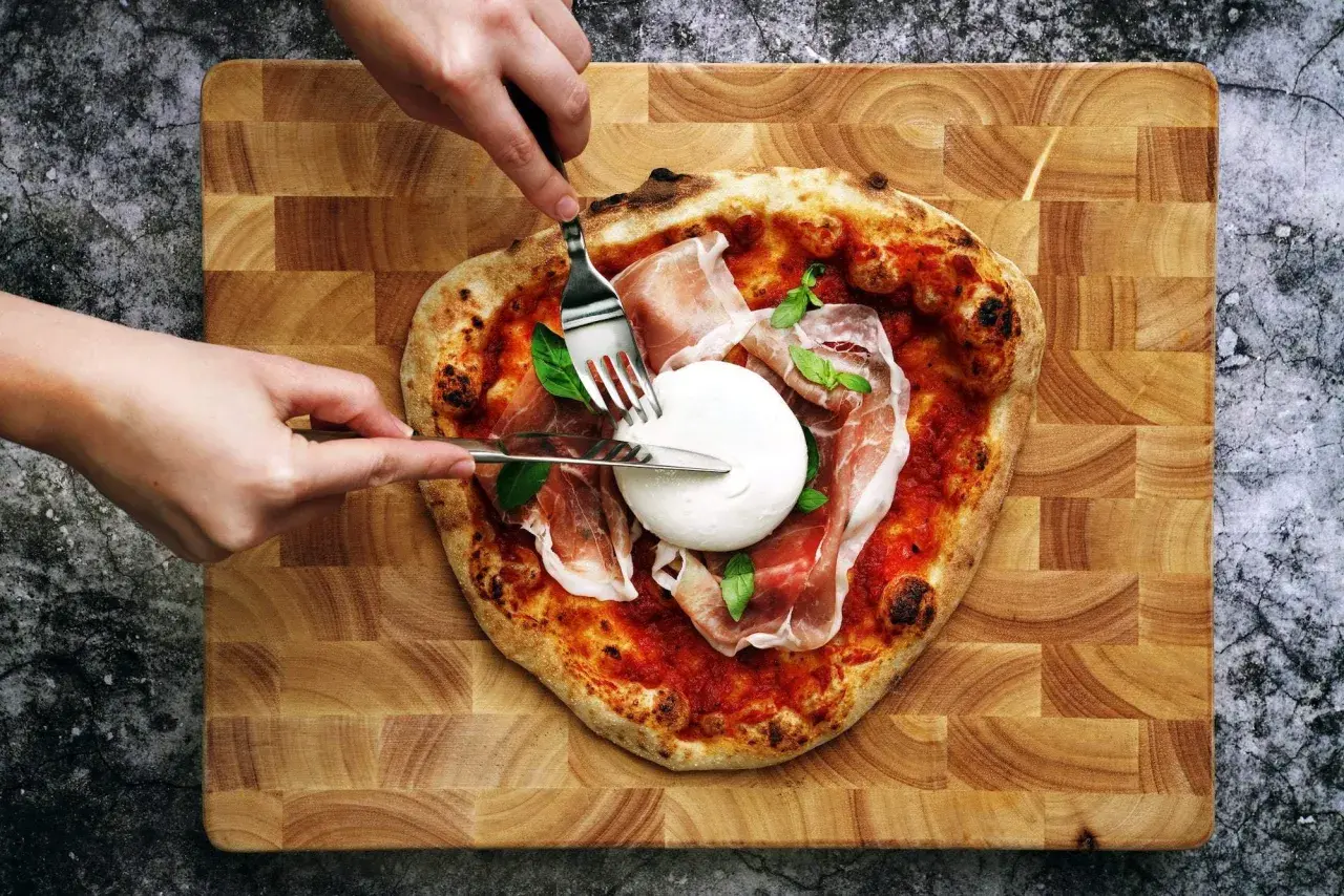 Une pizza burrata avec du prosciutto et du basilic, prête à être dégustée.