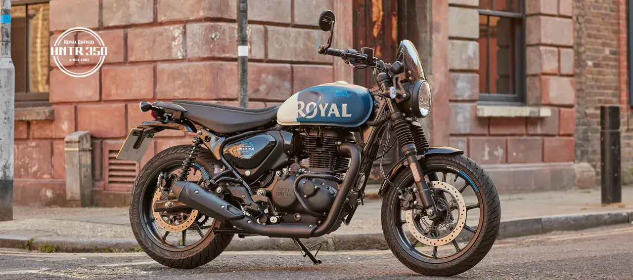 Stylowy motocykl Royal Enfield Hunter 350 z niebiesko-białym malowaniem zbiornika, zaparkowany na ulicy.
