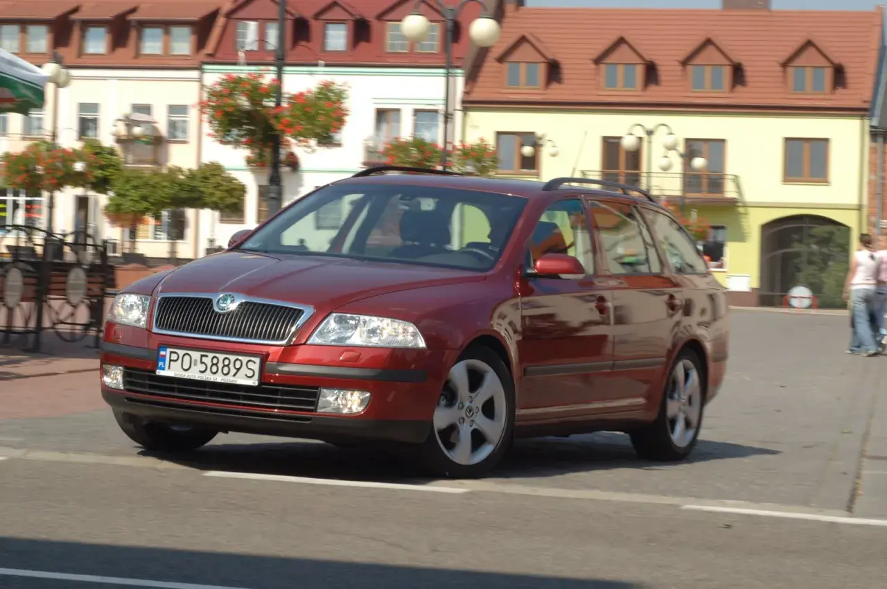 Czerwona Skoda Octavia 2 kombi na ulicy, z widocznymi żarówkami w przednich reflektorach.