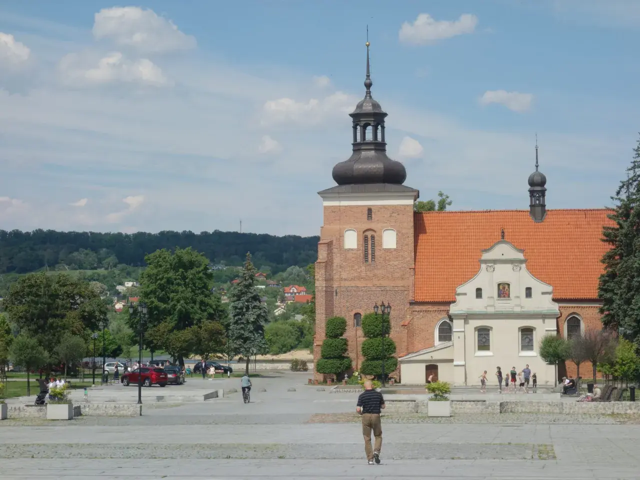 Włocławek atrakcje na weekend: plac z katedrą, spacerowicze, drzewa i zielone wzgórza w tle.